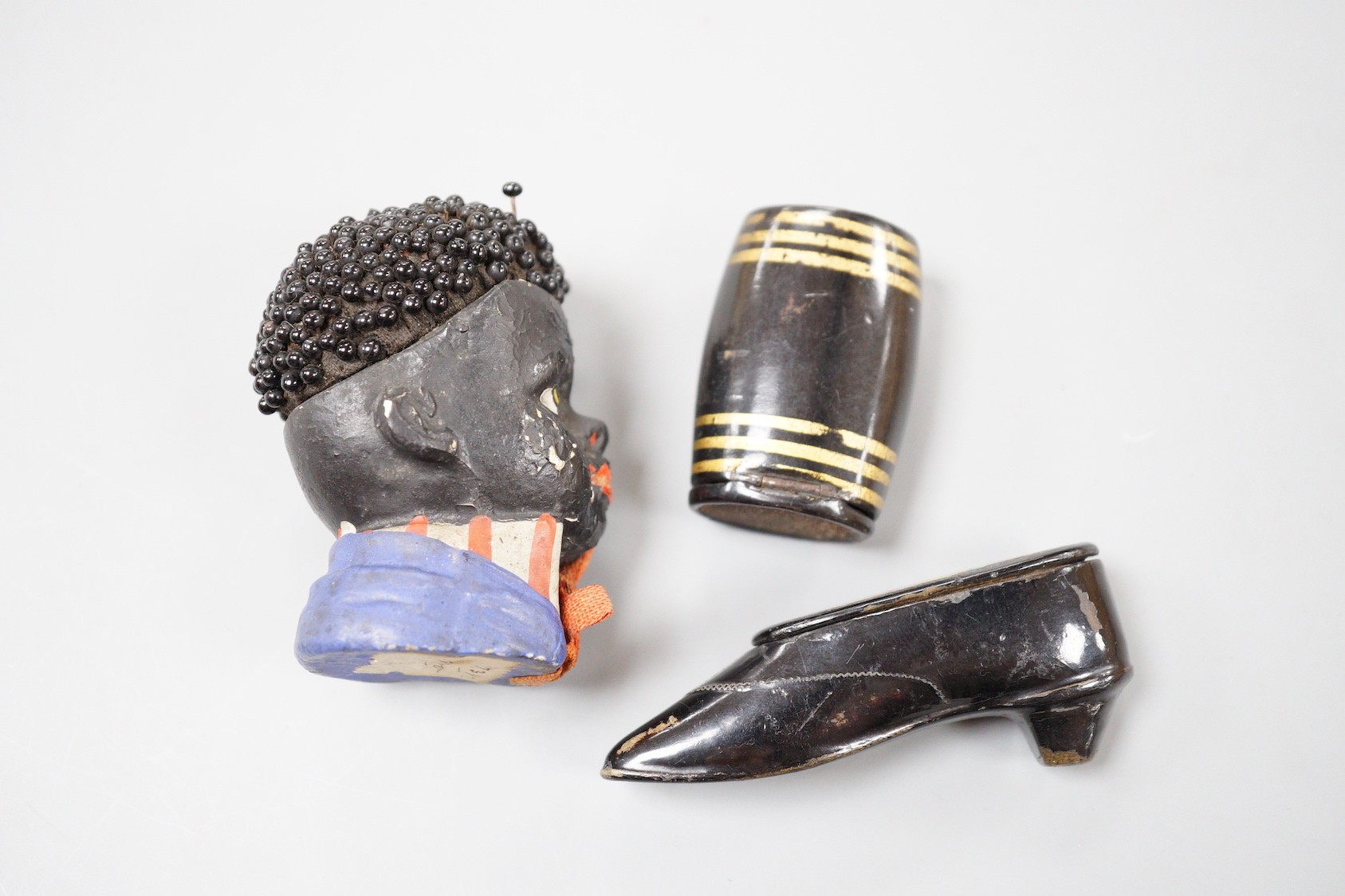 A Victorian japanned Papier mache snuff shoe, 7.5 cm, a similar Vesta case and novelty pin-cushion (3)